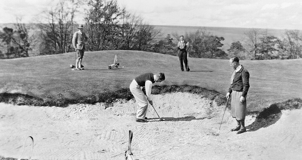 Black and white image of 4 golfers in a bunker
